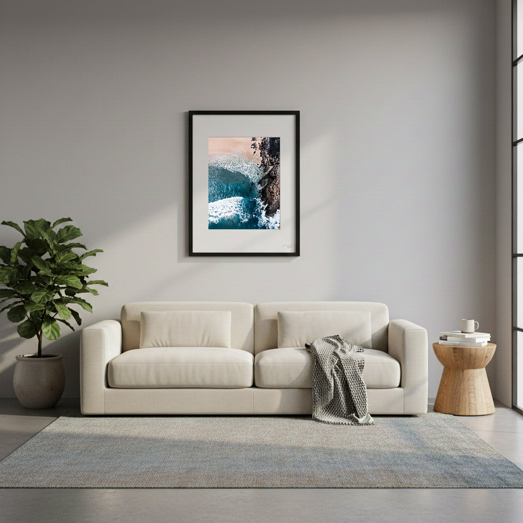 Framed top-down view of blue waves crashing against a rocky shore in Noosa, Queensland, Australia.