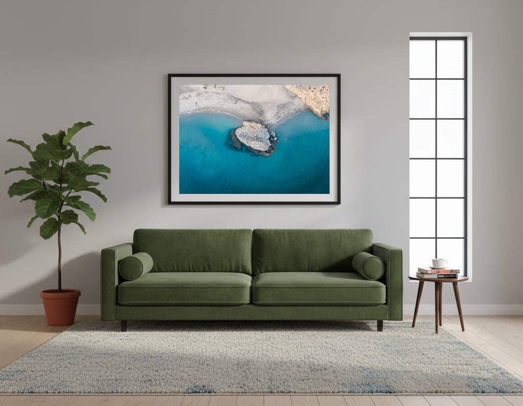 Framed aerial view of a rocky island in clear blue water with a white sandy beach in Cabo de Gata, Spain.