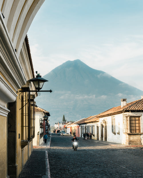 Cobbled street at dawn with buildings and a mountain in the background, Antigua, Guatemala.