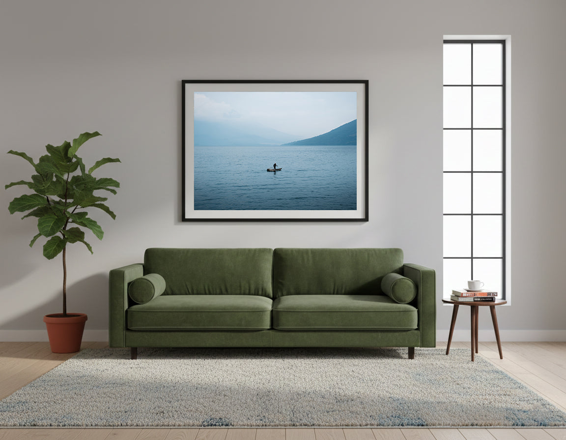 Framed person on a small fishing boat on a calm lake with mountains in the background, in Lake Atitlan, Guatemala.