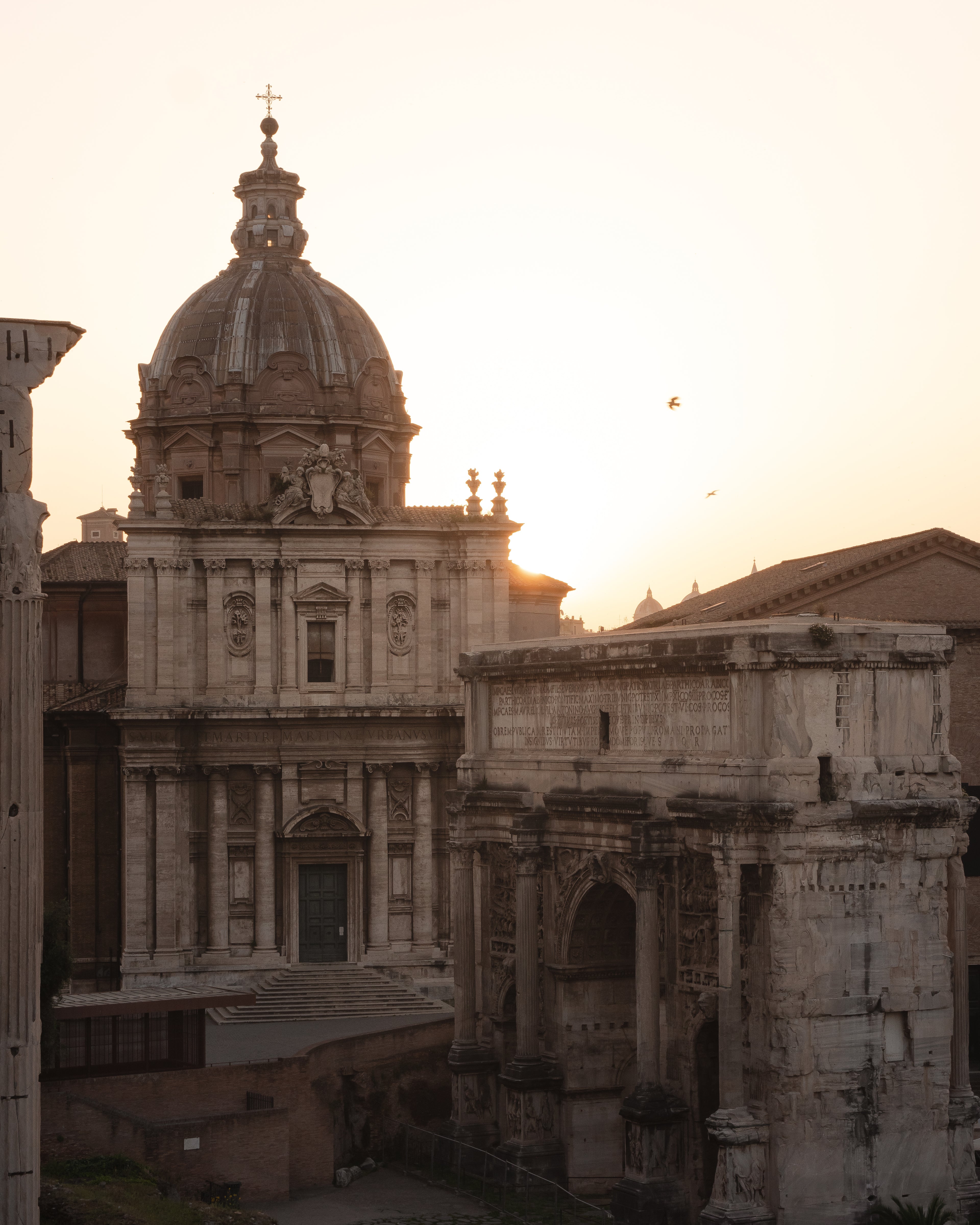 Historical architecture with a dome and ancient ruins at sunset.