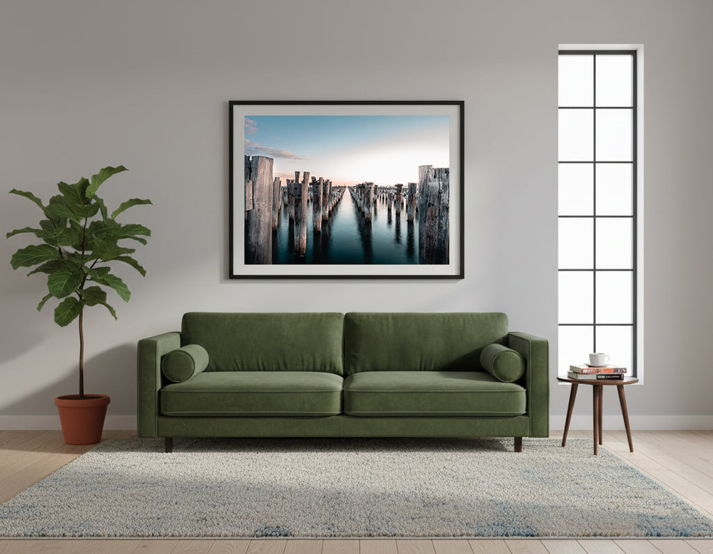 Framed long exposure of wooden pier posts extending into water with a soft sky in Princes Pier, Melbourne, Victoria, Australia.