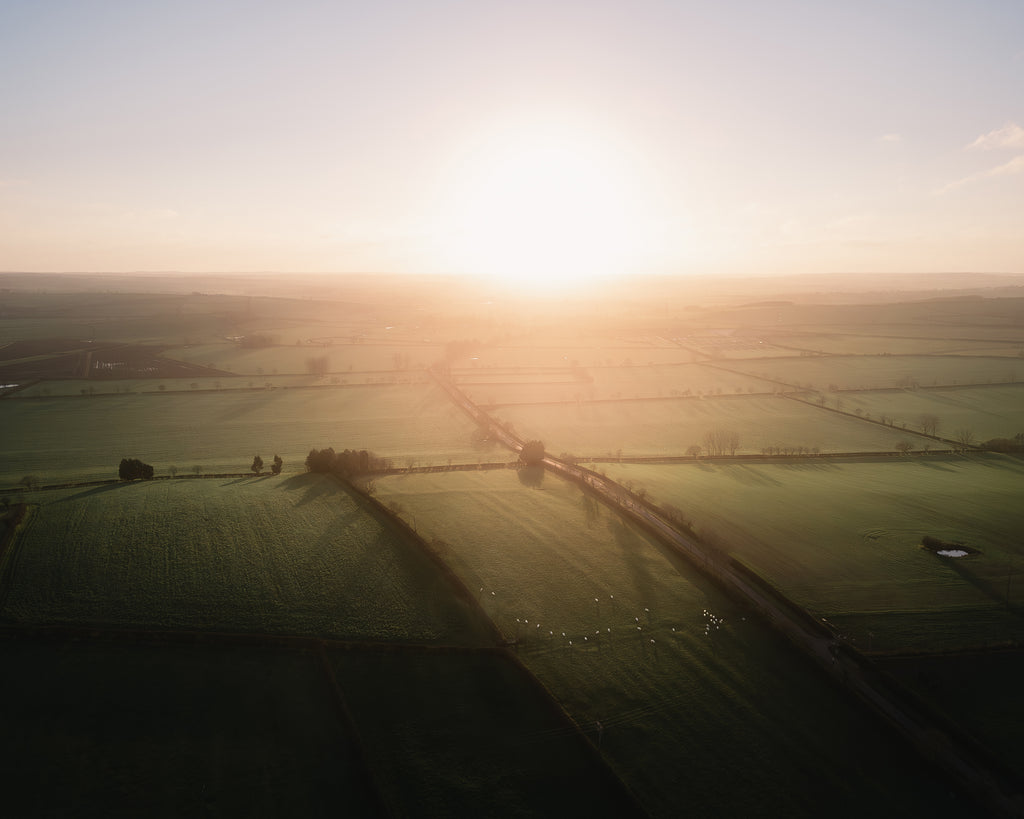Dramatic sunrise over a rural landscape with fields and a road in England, United Kingdom.