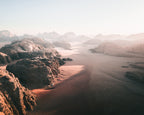 Desert aerial landscape with rocky formations and a vast expanse of sand at dawn, in Wadi Rum, Jordan.