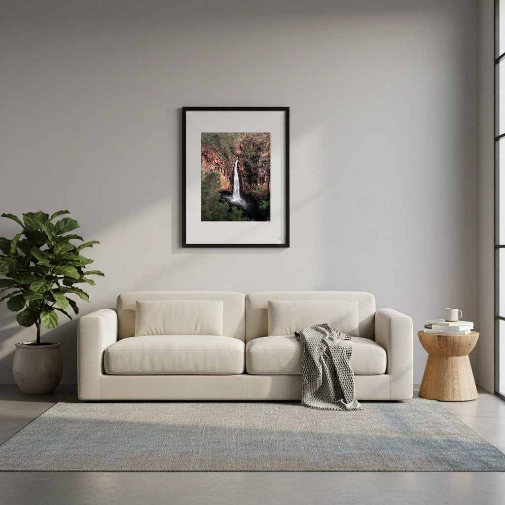 Framed waterfall cascading down a rocky cliff face with greenery around in Tolmer Falls, Litchfield National Park, Northern Australia.